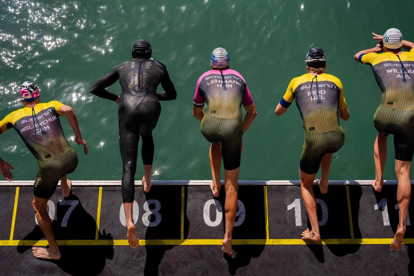Athletes lined up on the pontoon at a supertri swim start, seen from behind