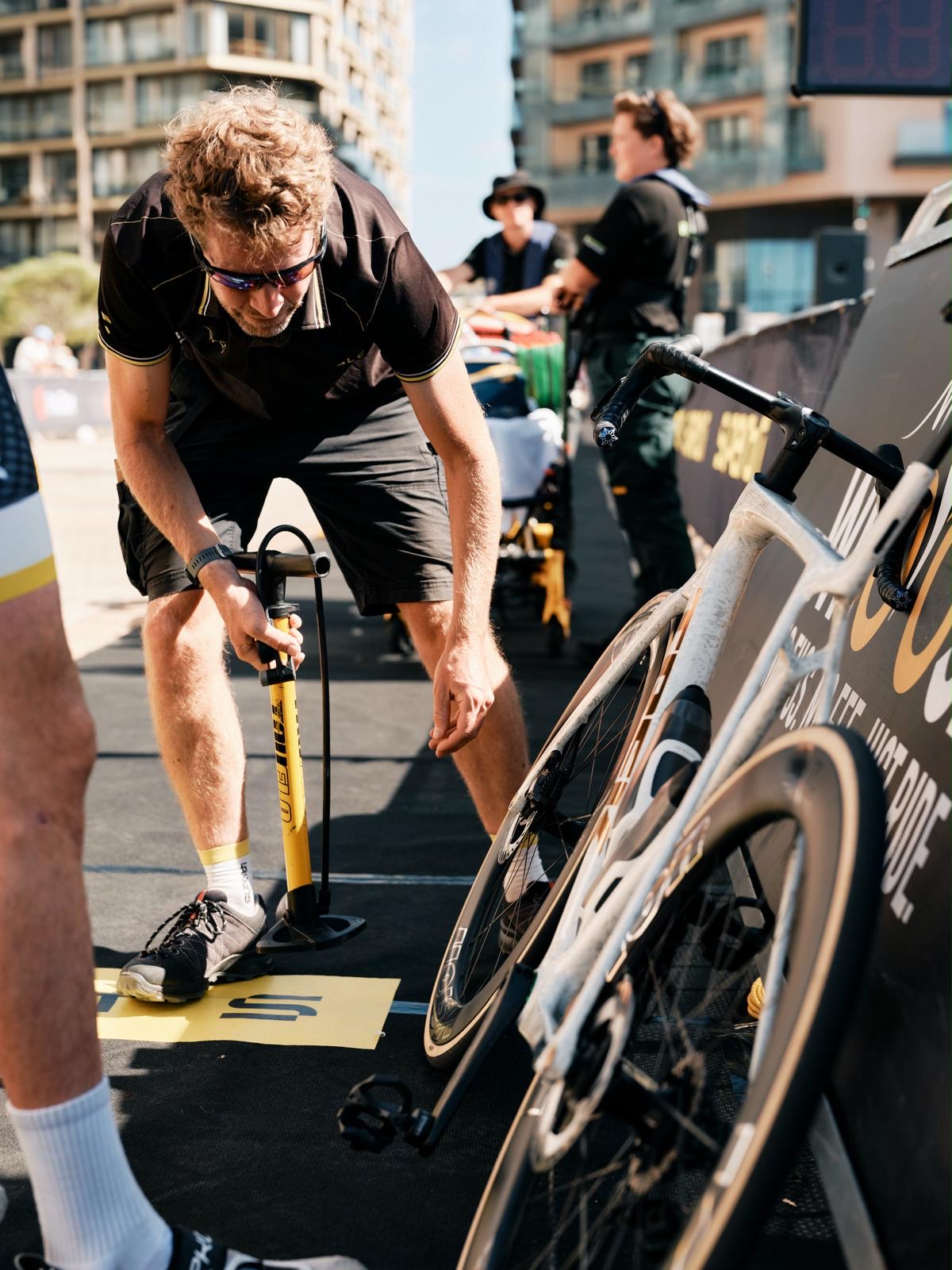 A mechanic checking tyre pressure in transition before a race